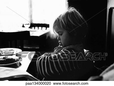 Young child sitting, arms crossed at table, side view, b&w. View Large Photo Image Stock Image - Young child sitting, arms crossed at table, side view, b&w.. Fotosearch
