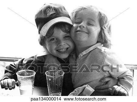 Young children sitting at table hugging, portrait, b&w. View Large Photo Image Picture - Young children sitting at table hugging, portrait, b&w.. Fotosearch
