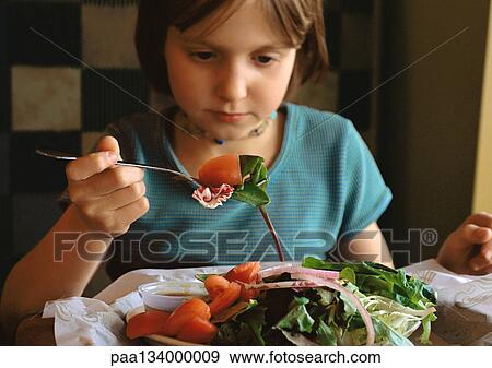 Stock Photo - Young girl eating salad, portrait.. Fotosearch