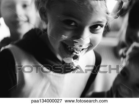 Young girl laughing with food on face, looking into camera, with other children, b&w. View Large Photo Image Stock Photo - Young girl laughing with food on face, looking into camera, with other children, b&w.. Fotosearch