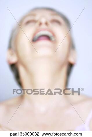 Stock Image - Mature woman laughing with head back, close-up, portrait, blurred. Fotosearch