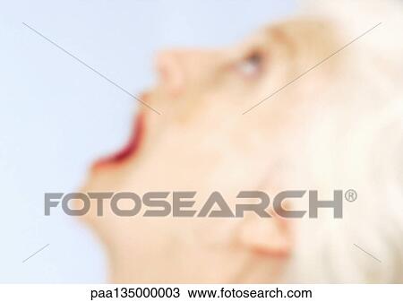 Stock Image - Mature woman with head back and mouth open, side view, close-up, portrait. Fotosearch