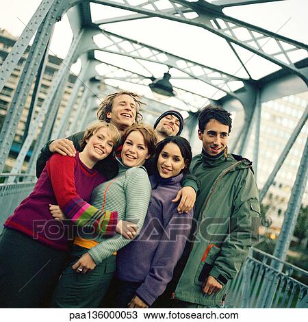 Stock Image - Group of young men and women with arms around each other . Fotosearch