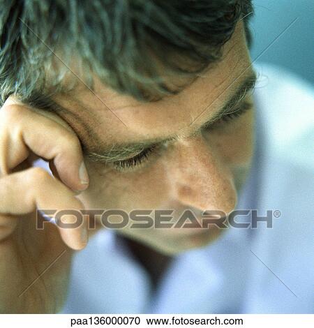 Stock Image - Man resting head against hand, eyes lowered, portrait. Fotosearch