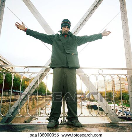 Stock Photography - Man standing on bridge with arms stretched out. Fotosearch