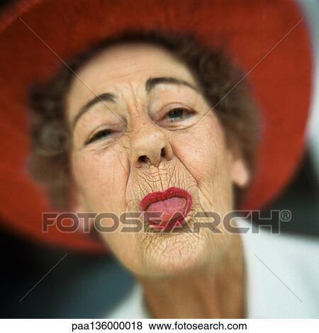 Portrait of senior woman wearing red hat with tongue sticking out View Large Photo Image Stock Photo - Portrait of senior woman wearing red hat with tongue sticking out. Fotosearch