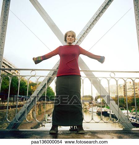 Woman standing on bridge with arms stretched out View Large Photo Image Picture - Woman standing on bridge with arms stretched out . Fotosearch