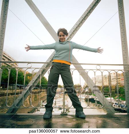 Woman standing on bridge with arms stretched out View Large Photo Image Stock Photo - Woman standing on bridge with arms stretched out . Fotosearch