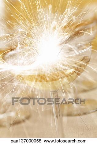 Stock Photo - Glass of Champagne and sparkler, close-up.. Fotosearch