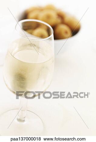 Stock Photo - Glass of white wine and bowl of olives.. Fotosearch