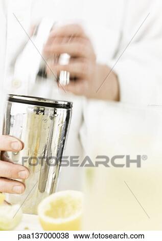 Stock Photo - Hands holding cocktail shaker, focus on cocktail shaker.. Fotosearch