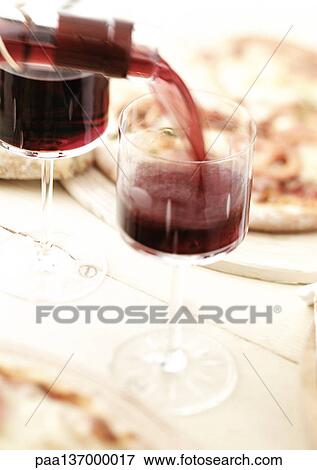 Stock Photo - Two glasses of red wine being poured.. Fotosearch