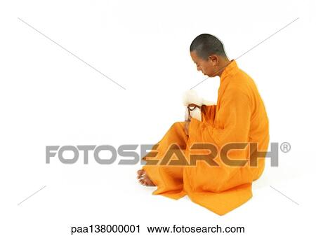 Stock Image - Buddhist monk sitting, side view. Fotosearch