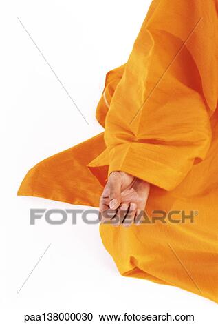 Stock Image - Buddhist monk's hand on knee in lotus position. Fotosearch