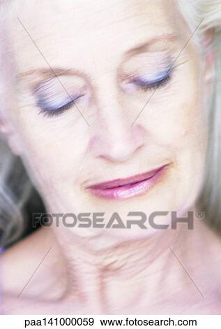 Stock Photo - Mature woman smiling, eyes closed, blurred, portrait.. Fotosearch