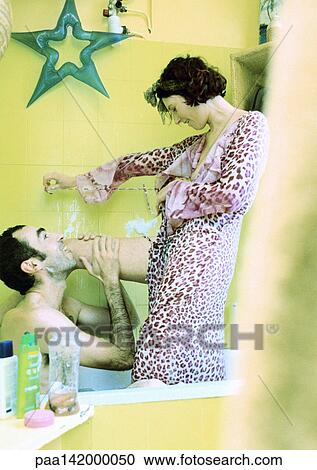 Couple in bath, woman standing, wearing robe, man holding her leg. View Large Photo Image Stock Image - Couple in bath, woman standing, wearing robe, man holding her leg.. Fotosearch