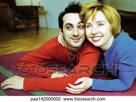 Stock Image - Couple lying on floor, smiling.. Fotosearch