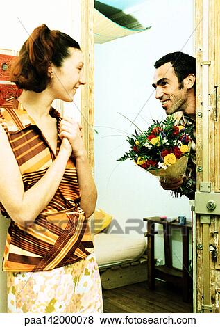 Couple, man walking through door holding bouquet of flowers, woman smiling. View Large Photo Image Stock Photo - Couple, man walking through door holding bouquet of flowers, woman smiling.. Fotosearch