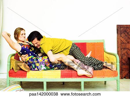Couple on sofa, man pouncing on woman, woman with arm ready to strike View Large Photo Image Stock Photo - Couple on sofa, man pouncing on woman, woman with arm ready to strike. Fotosearch
