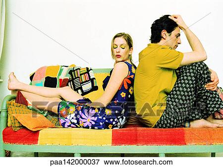Stock Photo - Couple sitting on sofa, back to back.. Fotosearch