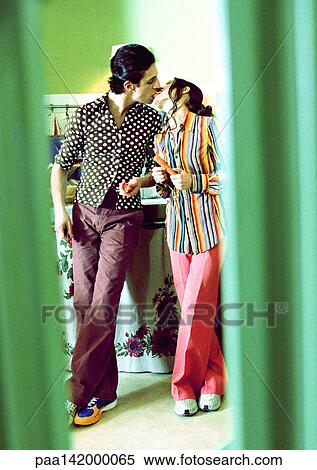 Stock Photography - Couple standing in kitchen, kissing.. Fotosearch