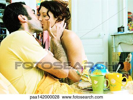 Man in bed with breakfast tray on lap, kissing woman, side view. View Large Photo Image Stock Photo - Man in bed with breakfast tray on lap, kissing woman, side view.. Fotosearch