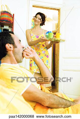 Man in bed yawning, woman carrying breakfast tray. View Large Photo Image Stock Photo - Man in bed yawning, woman carrying breakfast tray.. Fotosearch