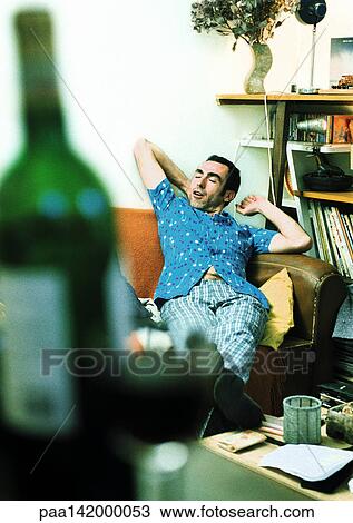 Man stretching on sofa, bottle of wine in foreground View Large Photo Image Stock Image - Man stretching on sofa, bottle of wine in foreground. Fotosearch
