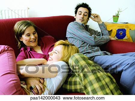 Two women playing on sofa, man sitting watching. View Large Photo Image Stock Image - Two women playing on sofa, man sitting watching.. Fotosearch