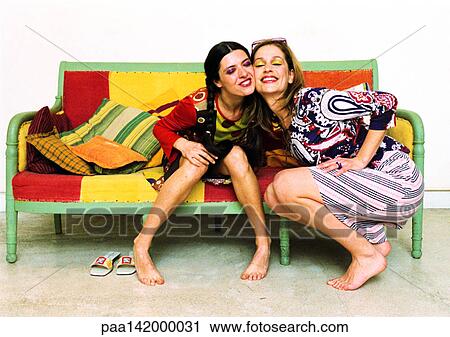 Two young women on sofa, cheek to cheek, smiling. View Large Photo Image Stock Image - Two young women on sofa, cheek to cheek, smiling.. Fotosearch