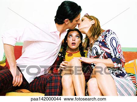 Young couple about to kiss, woman sitting between them watching. View Large Photo Image Picture - Young couple about to kiss, woman sitting between them watching.. Fotosearch