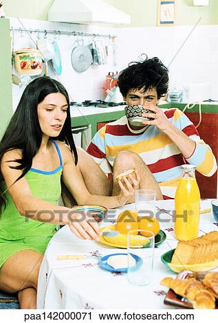 Young couple sitting at table having breakfast. View Large Photo Image Stock Image - Young couple sitting at table having breakfast.. Fotosearch