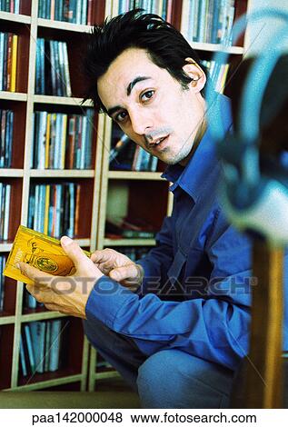 Young man in front of cd collection, looking into camera, portrait. View Large Photo Image Stock Photo - Young man in front of cd collection, looking into camera, portrait.. Fotosearch