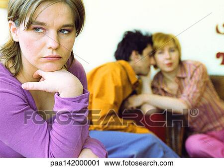 Young woman frowning, hand under chin, couple cuddling in background. View Large Photo Image Stock Image - Young woman frowning, hand under chin, couple cuddling in background.. Fotosearch