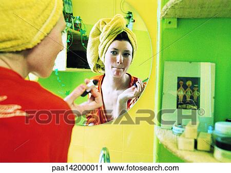 Young woman putting on make-up, focus on reflection in mirror. View Large Photo Image Stock Image - Young woman putting on make-up, focus on reflection in mirror.. Fotosearch