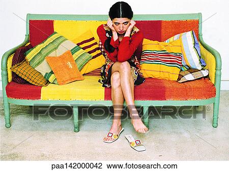 Young woman sitting on sofa looking into camera. View Large Photo Image Stock Image - Young woman sitting on sofa looking into camera.. Fotosearch