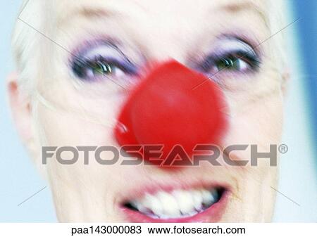 Stock Image - Mature woman wearing clown nose, close-up, blurred. Fotosearch
