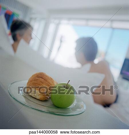 Apple and croissant on plate, people in background View Large Photo Image Stock Photo - Apple and croissant on plate, people in background. Fotosearch
