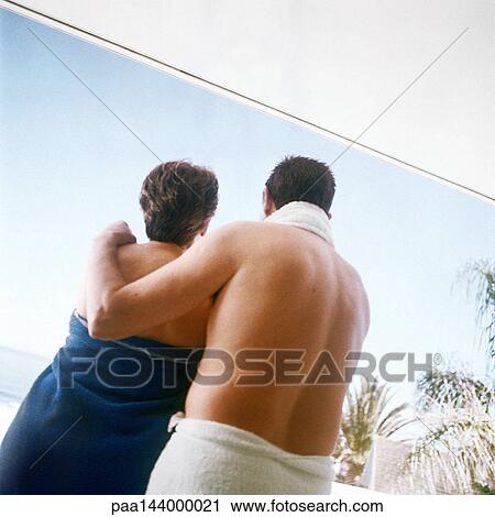 Stock Image - Couple standing with towels wrapped around them, rear view. Fotosearch