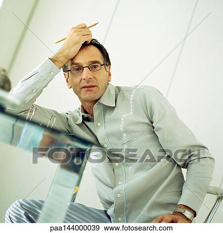 Man leaning on table with hand on head View Large Photo Image Stock Photo - Man leaning on table with hand on head. Fotosearch