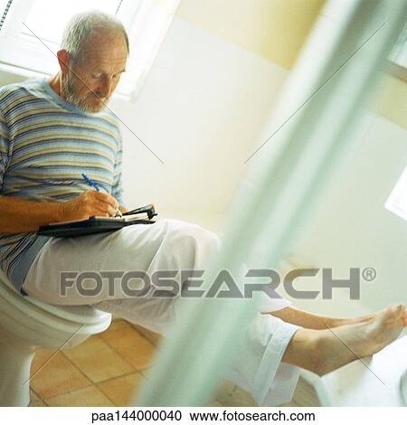 Man sitting on toilet, writing with feet up View Large Photo Image Stock Image - Man sitting on toilet, writing with feet up. Fotosearch