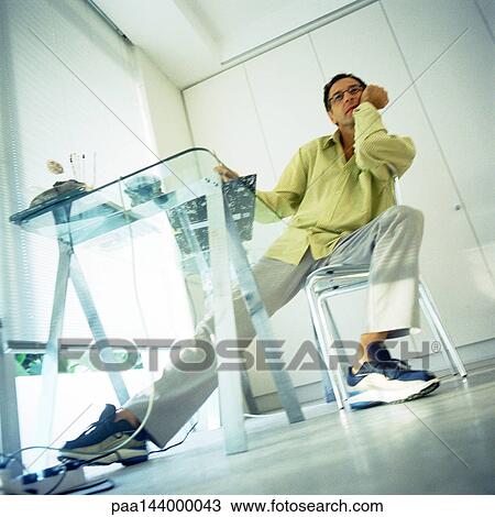 Man sitting with hand under chin, low angle view View Large Photo Image Stock Image - Man sitting with hand under chin, low angle view. Fotosearch