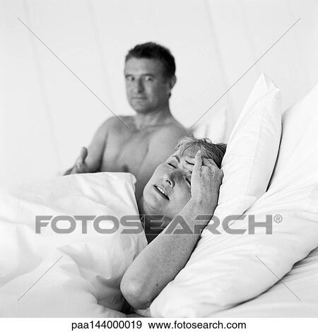 Mature couple in bed, woman holding head, b&w View Large Photo Image Stock Photo - Mature couple in bed, woman holding head, b&w. Fotosearch