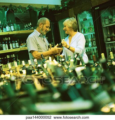 Mature couple looking at wine bottle in wine store View Large Photo Image Stock Image - Mature couple looking at wine bottle in wine store. Fotosearch