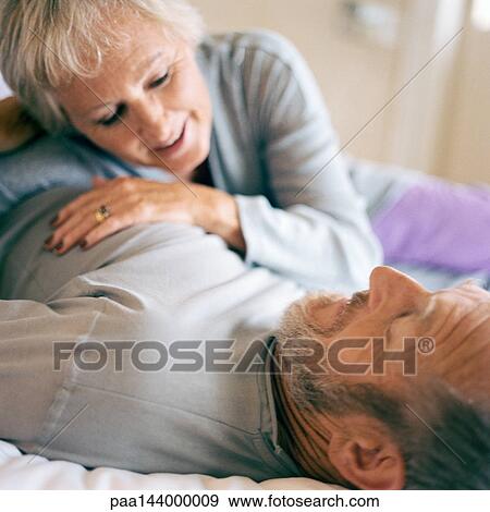 Mature couple lying down, woman leaning on man's stomach View Large Photo Image Stock Photo - Mature couple lying down, woman leaning on man's stomach. Fotosearch