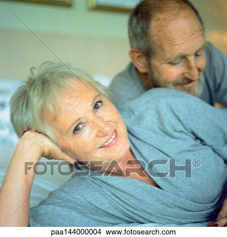 Mature couple lying down, woman looking into camera View Large Photo Image Picture - Mature couple lying down, woman looking into camera. Fotosearch
