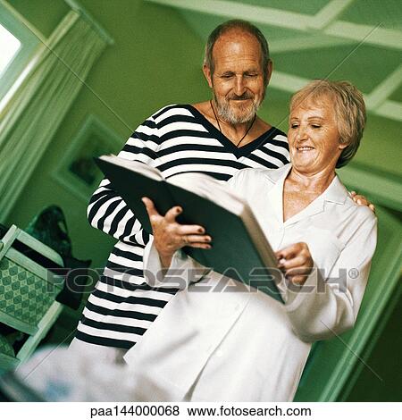 Mature man and woman looking at book View Large Photo Image Stock Photo - Mature man and woman looking at book. Fotosearch