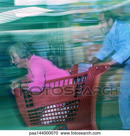 Mature man pushing woman in shopping cart, blurred motion View Large Photo Image Stock Image - Mature man pushing woman in shopping cart, blurred motion. Fotosearch