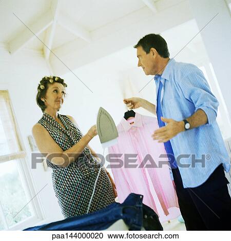 Mature woman holding iron, man holding shirt View Large Photo Image Stock Image - Mature woman holding iron, man holding shirt. Fotosearch