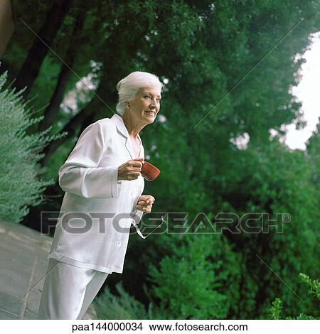 Mature woman holding teacup, outside View Large Photo Image Picture - Mature woman holding teacup, outside. Fotosearch